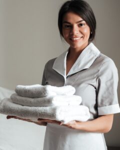 Portrait of a smiling hotel maid holding fresh clean folded towels for the room